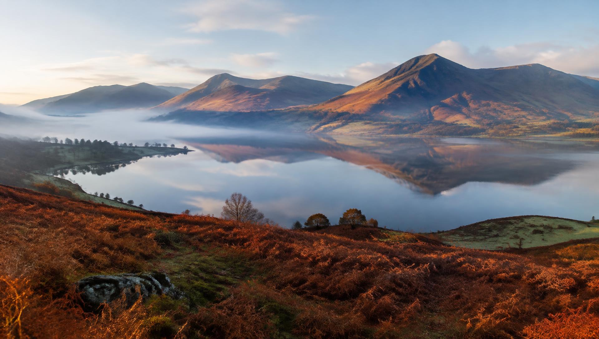 Still lake reflecting autumn fells